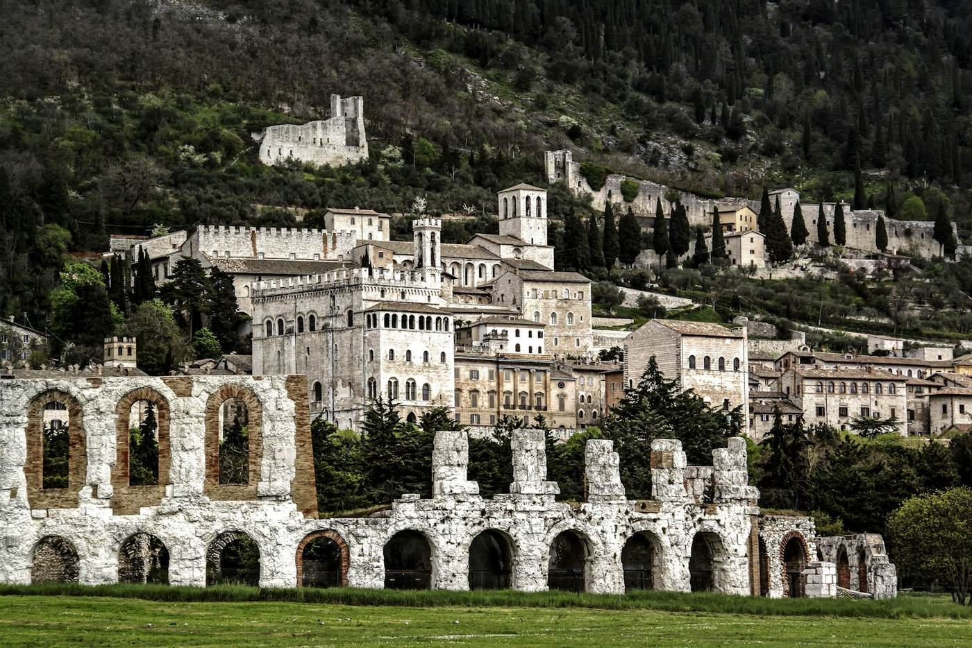 Le arcate del Teatro romano di Gubbio con il centro storico e il Palazzo dei Consoli sullo sfondo