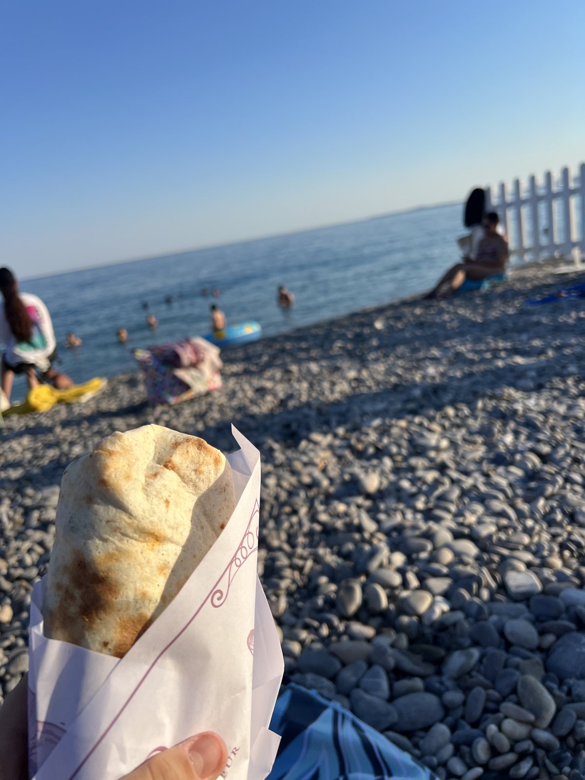 Un panino di Maison Armand sulla spiaggia di ciottoli di Nizza, con il mare sullo sfondo